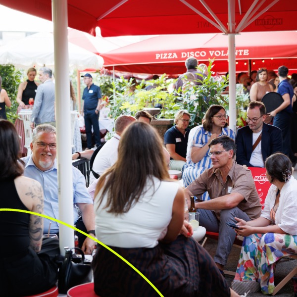 bvitg Sommerfest 2026, Menschen sitzen unter roten schirmen und unterhalten sich