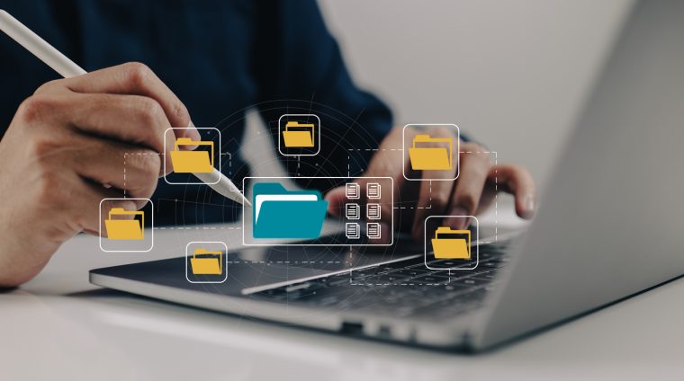 Laptop und Akten in blau und gelb als Icons über der Tastaturt zu sehen